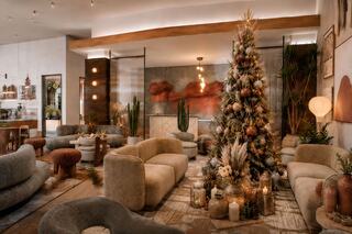 A cozy holiday lounge featuring a beautifully decorated Christmas tree, plush seating, warm lighting, and elegant decorative accents.