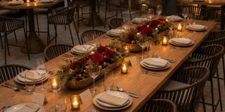 A beautifully set long dining table adorned with floral arrangements and candles, creating an inviting atmosphere for a gathering.
