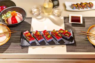 A beautifully arranged sushi platter featuring colorful pieces, garnishes, and sauces, complemented by sake and additional sushi dishes.