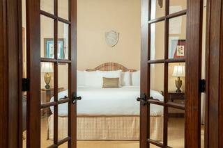A warmly decorated bedroom features a plush bed, bedside lamps, and tasteful artwork, creating an inviting and cozy atmosphere.