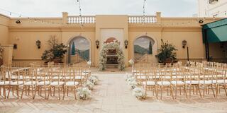 A beautifully arranged outdoor wedding venue with elegant seating, floral decorations, and a scenic backdrop of mountains and greenery.