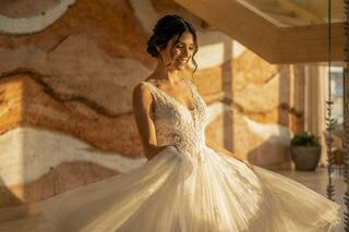 A bride smiles joyfully in a beautiful gown, illuminated by warm sunlight against a stunning natural backdrop.