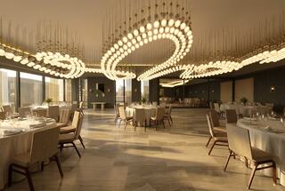A stylish dining area with elegant tables, plush chairs, and a striking chandelier design that creates an upscale ambiance.