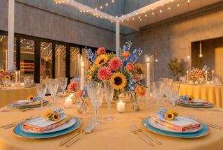 A beautifully set dining area with vibrant floral centerpieces, elegant glassware, and soft lighting, creating a warm, inviting ambiance.