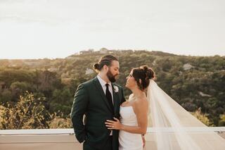 A radiant couple shares a romantic moment, surrounded by nature, with the sun setting behind them, highlighting their joy and love.
